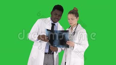 年轻的女医生和美国黑人医生看着绿色屏幕上肺部的x射线照片，ChromaKey。